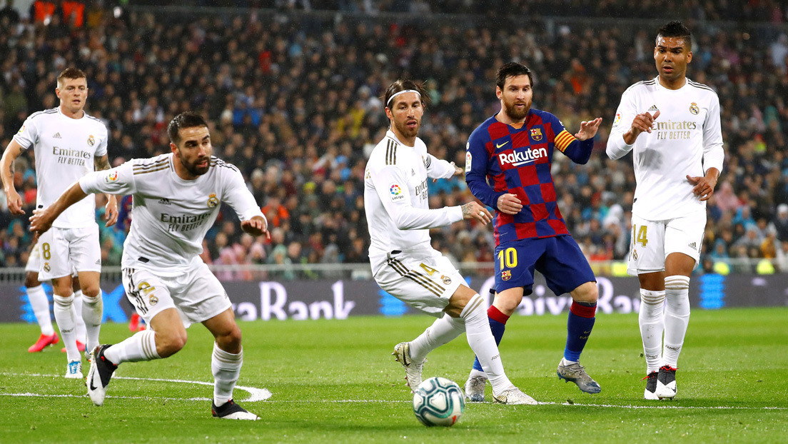 Jugadores de fútbol profesional de los equipos Real Madrid y FC Barcelona se enfrentan en el campo.
